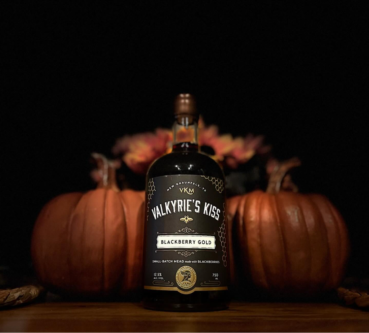 A bottle of Valkyrie's Kiss  Blackberry Gold mead, sitting with pumpkins.